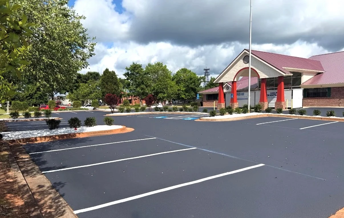 New asphalt parking lot with white striping, concrete curbs, and landscaped islands