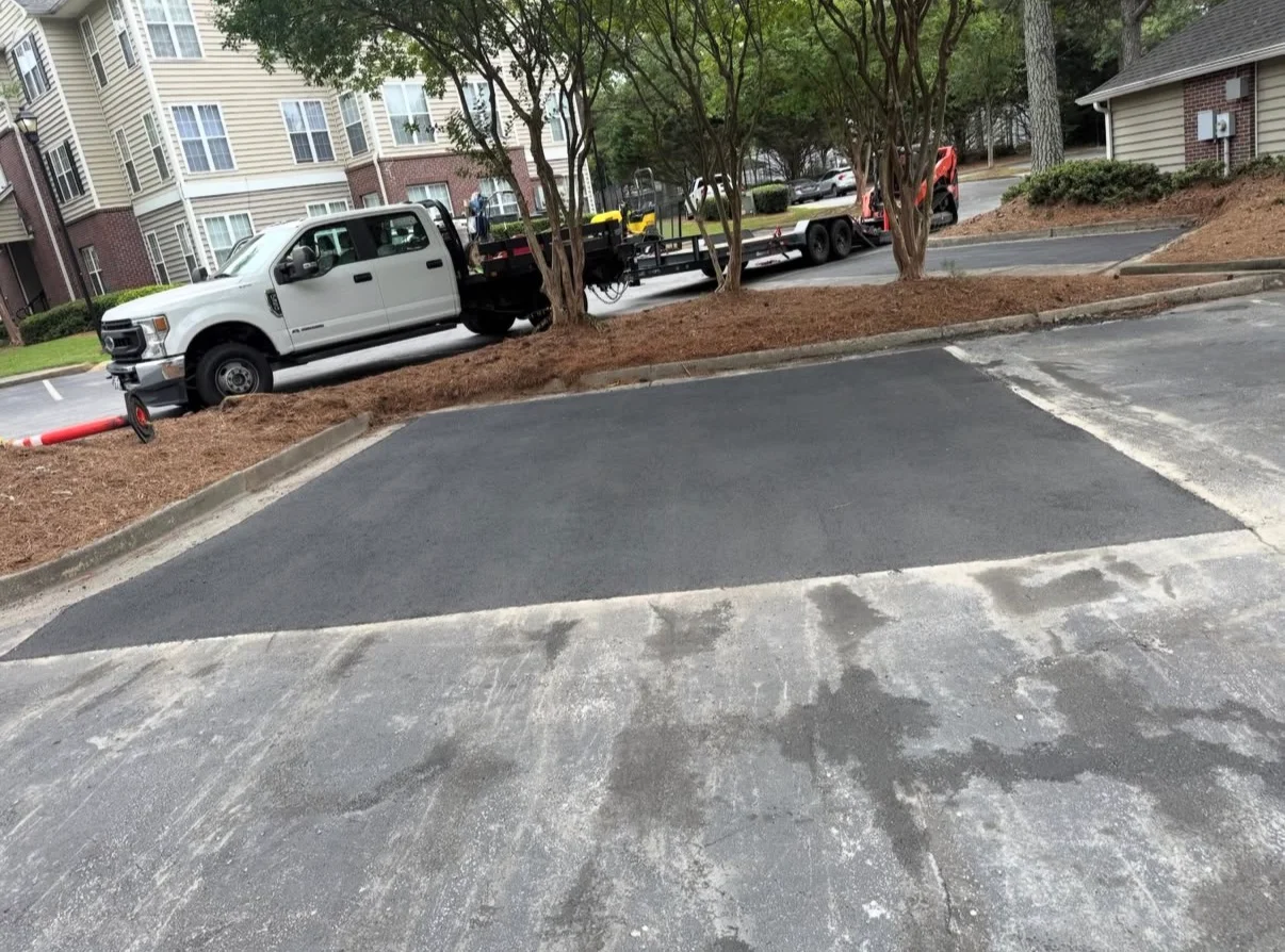 New asphalt driveway with concrete borders and mulch landscaping in residential setting