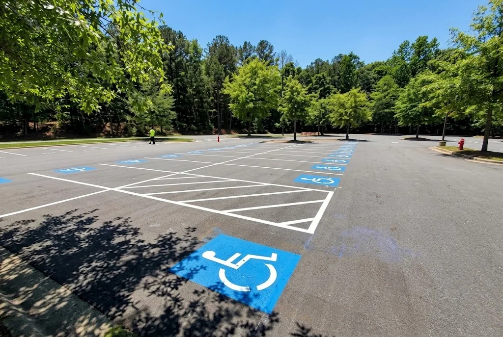 Asphalt parking lot with white striping, blue handicap spaces, and numbered parking markings