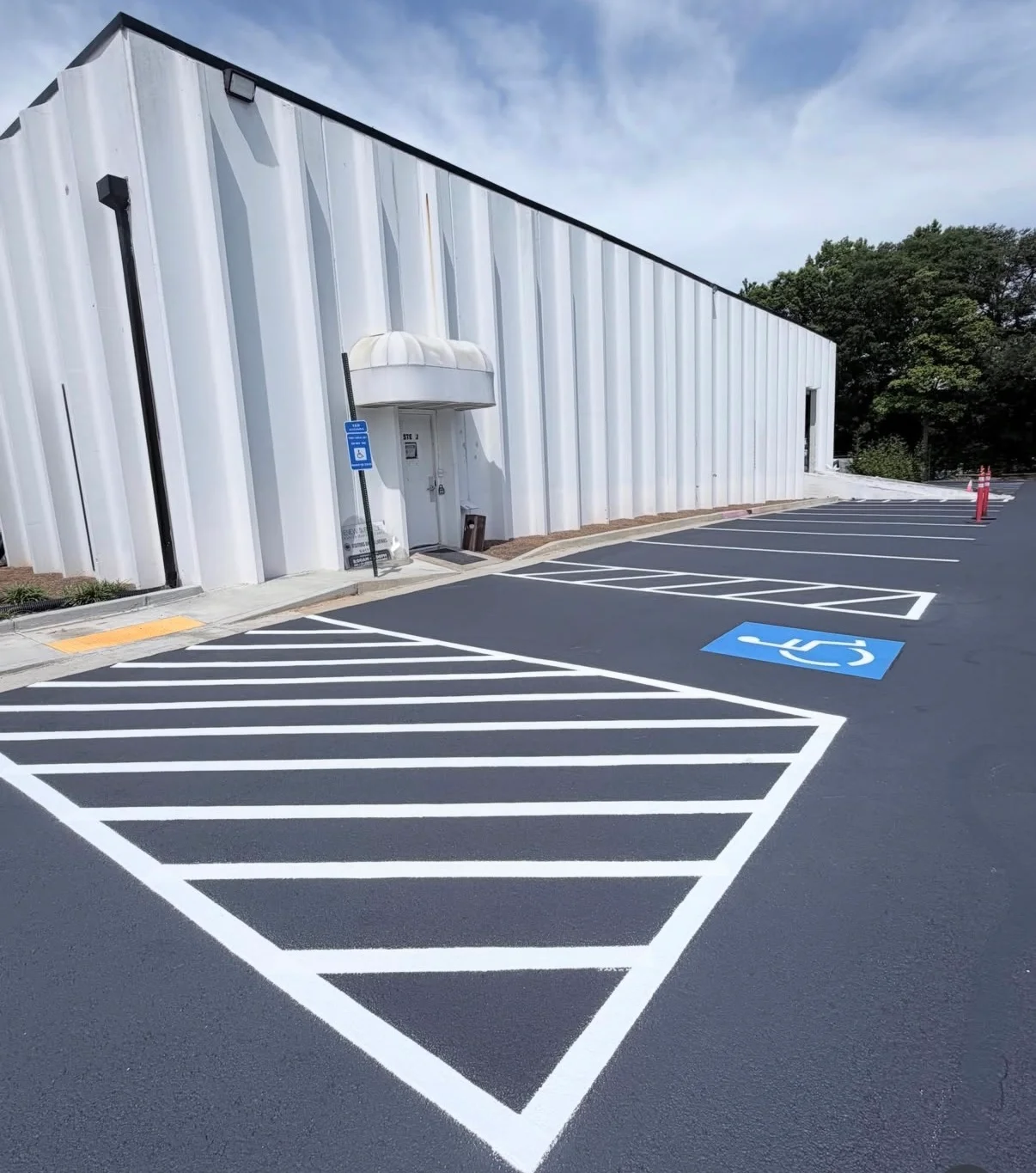 Newly paved asphalt parking lot with white striped spaces and blue ADA accessible parking symbol