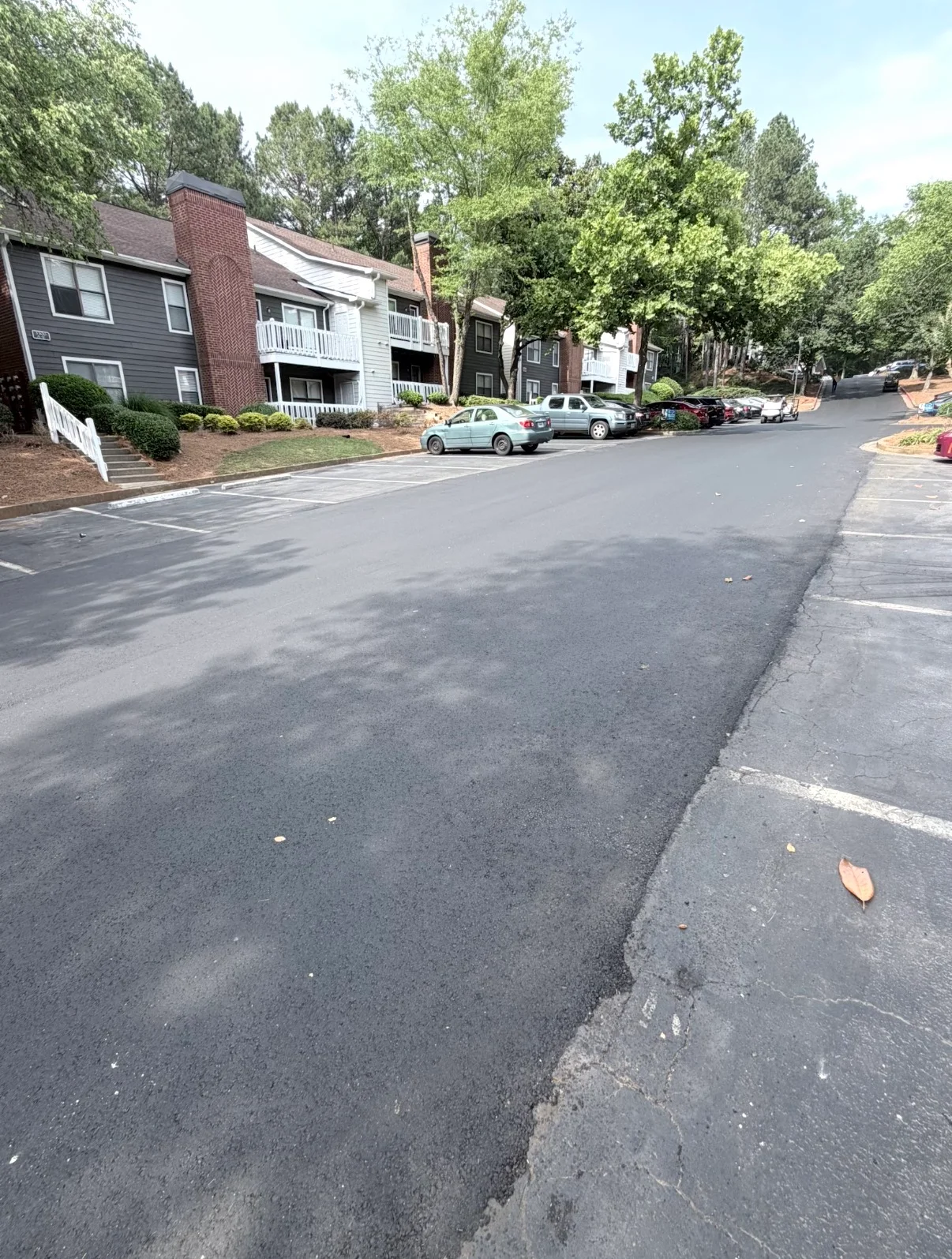 Newly paved asphalt street with dark finish and concrete curbing in residential community