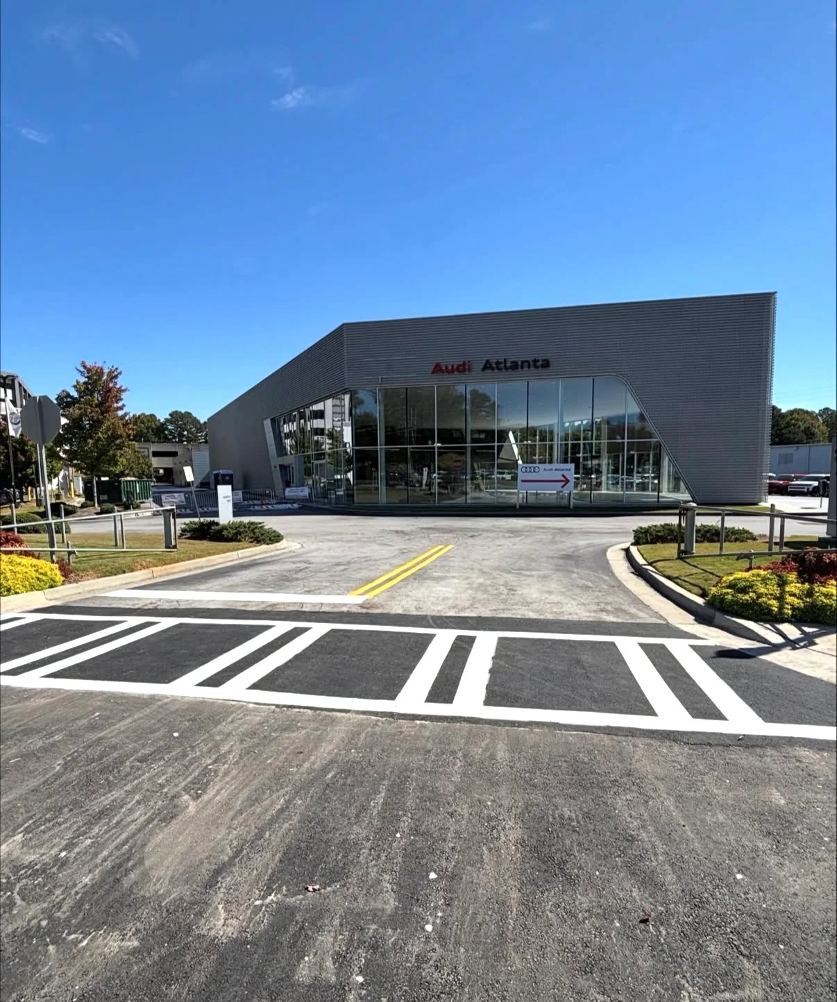 Newly paved asphalt parking lot with white striped spaces and yellow lane markings at commercial building