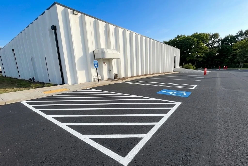 Newly paved asphalt parking lot with white striping and handicap space marking in front of commercial building