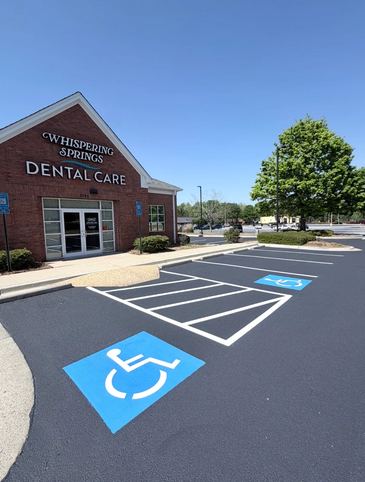 Newly paved asphalt parking lot with white striped spaces and blue ADA handicap markings