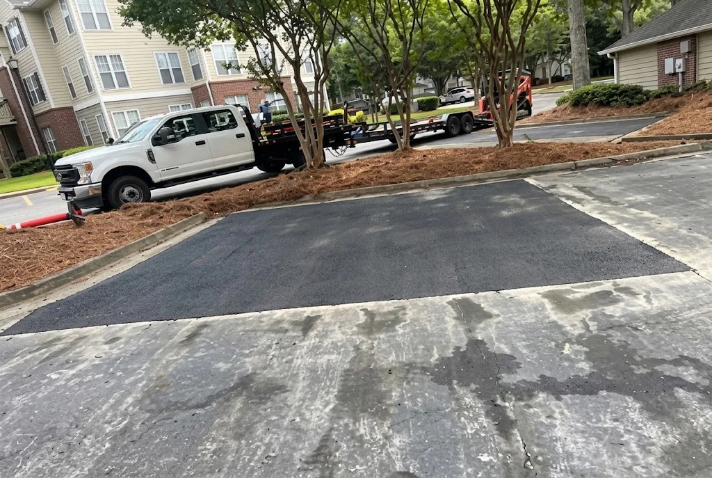 Newly paved black asphalt driveway with concrete apron and mulched landscaping borders